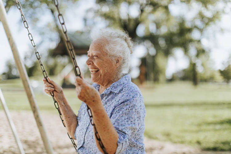 Cheerful senior woman on a swing at a playground